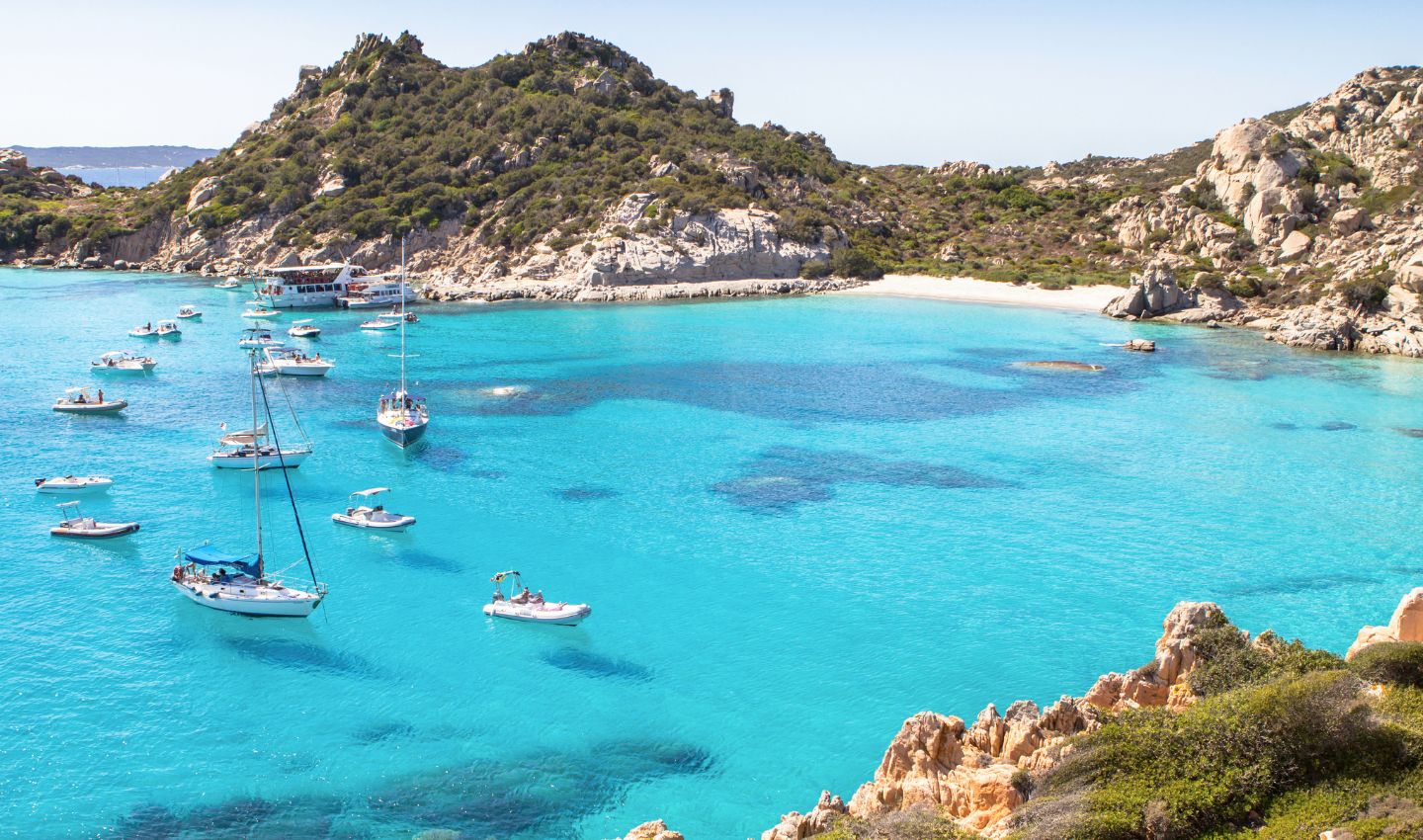 Eine traumhafte, von mediterranen Felsen umgebene Badebucht mit glasklarem, türkisblauem Wasser, in der weiße Segelboote und Jachten vor Anker liegen – ideal für die Frage, welches Urlaubsland am Meer am besten zu dir passt. Plane deinen nächsten Italien oder Kroatien Urlaub ganz entspannt und buche deine Reise mit Abflug ab Wien, Graz, Linz, Salzburg oder Innsbruck samt unserer verlässlichen Bestpreisgarantie direkt online bei der Restplatzbörse.